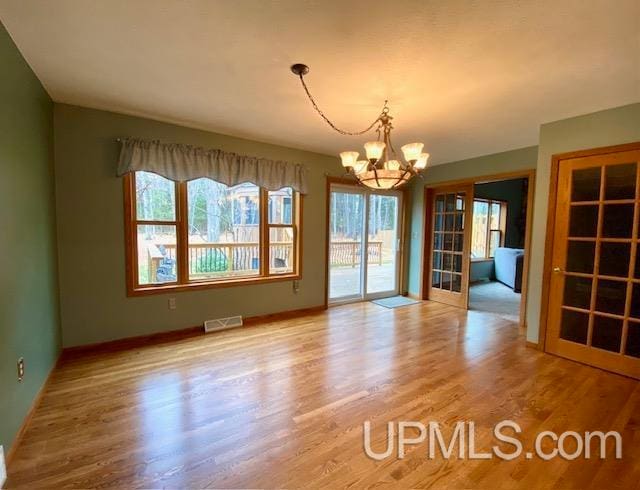 unfurnished dining area with light hardwood / wood-style floors and a notable chandelier