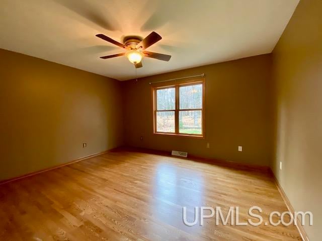 spare room with light wood-type flooring and ceiling fan