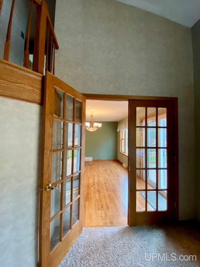 doorway with wood-type flooring, vaulted ceiling, french doors, and a notable chandelier