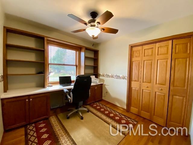 office space with dark hardwood / wood-style floors, ceiling fan, and built in desk