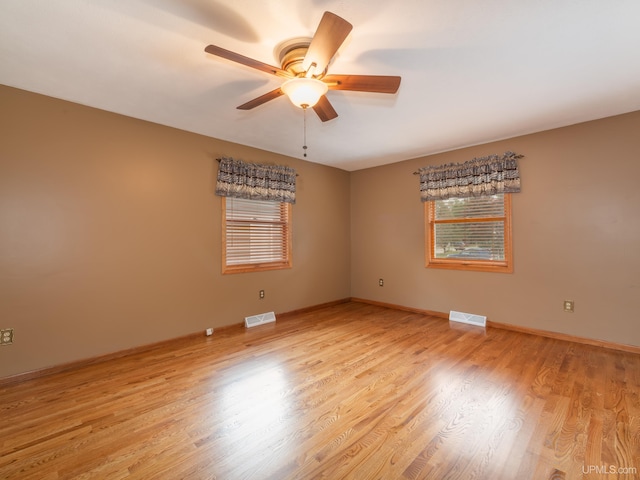 empty room with light wood-type flooring, ceiling fan, and a healthy amount of sunlight