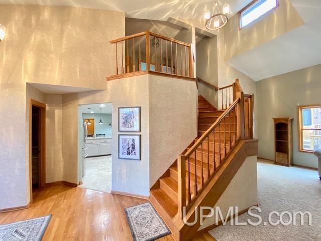 stairway featuring plenty of natural light, a towering ceiling, and hardwood / wood-style flooring