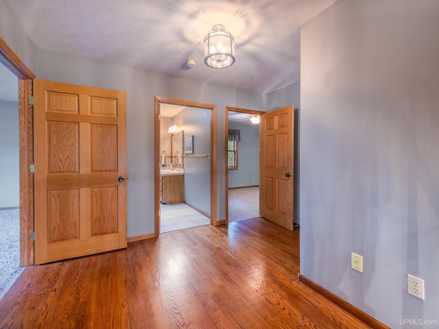 interior space with a chandelier, a textured ceiling, light hardwood / wood-style floors, and sink