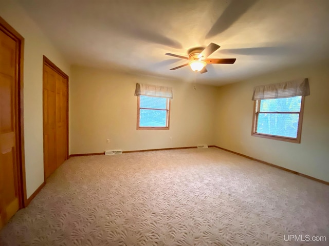 carpeted empty room featuring a wealth of natural light and ceiling fan