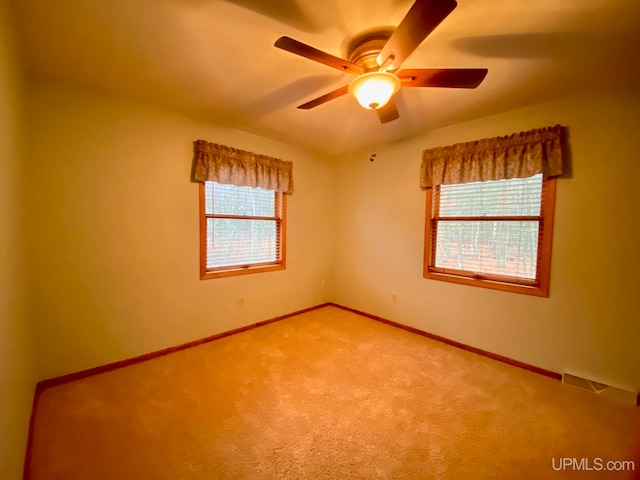 carpeted spare room with a wealth of natural light and ceiling fan