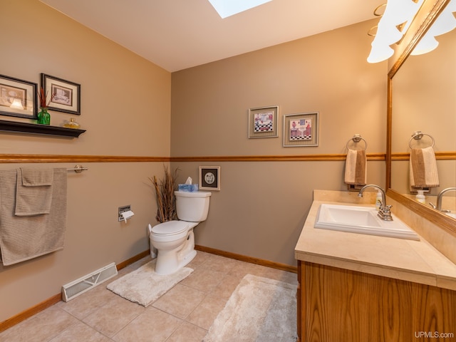 bathroom featuring tile patterned flooring, vanity, a skylight, and toilet