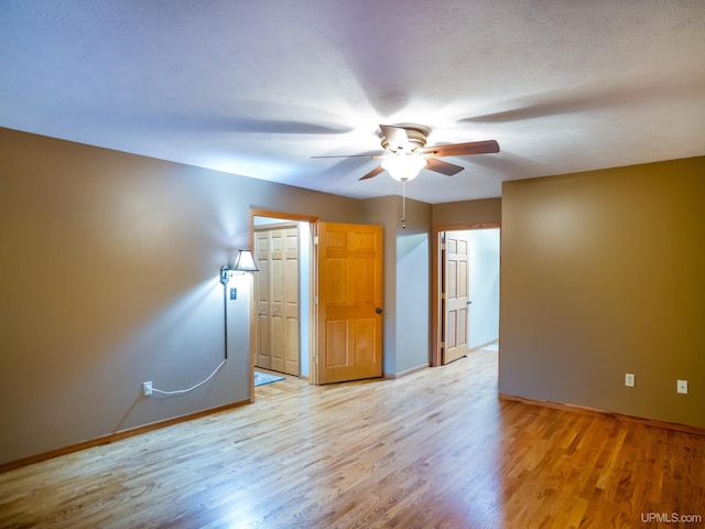 spare room with a textured ceiling, light hardwood / wood-style floors, and ceiling fan