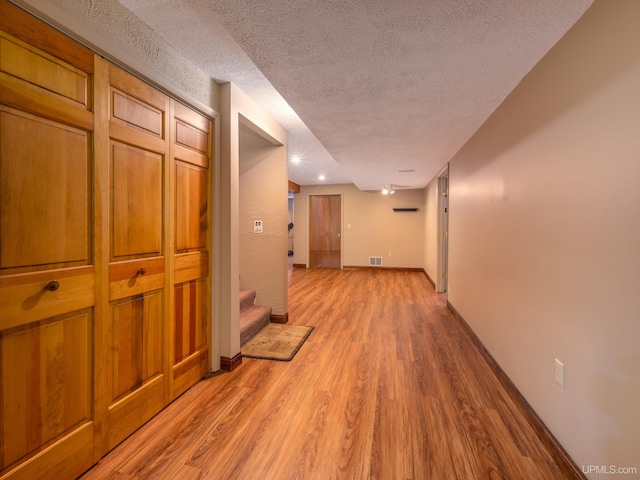 hallway featuring light hardwood / wood-style floors and a textured ceiling