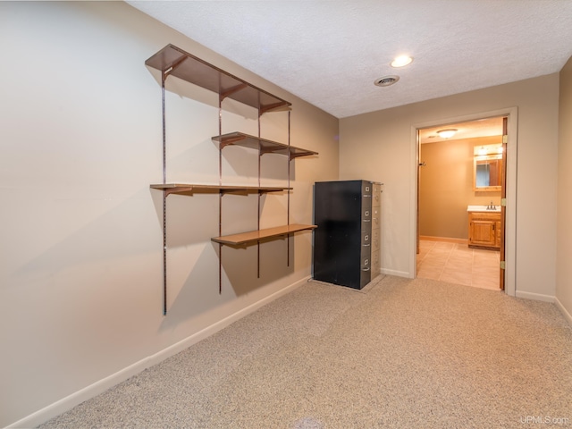 basement with sink, light colored carpet, and a textured ceiling