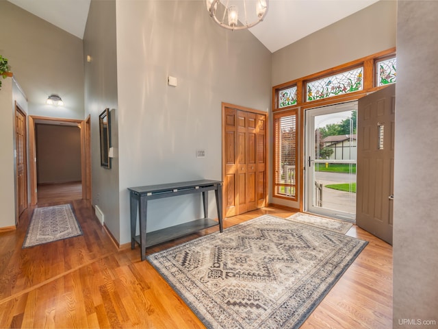 foyer entrance featuring high vaulted ceiling, light hardwood / wood-style floors, and an inviting chandelier