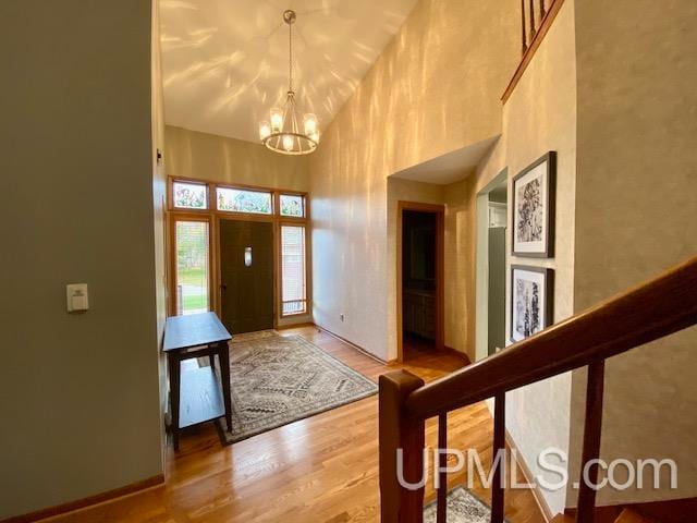 entryway with hardwood / wood-style flooring, a high ceiling, and an inviting chandelier