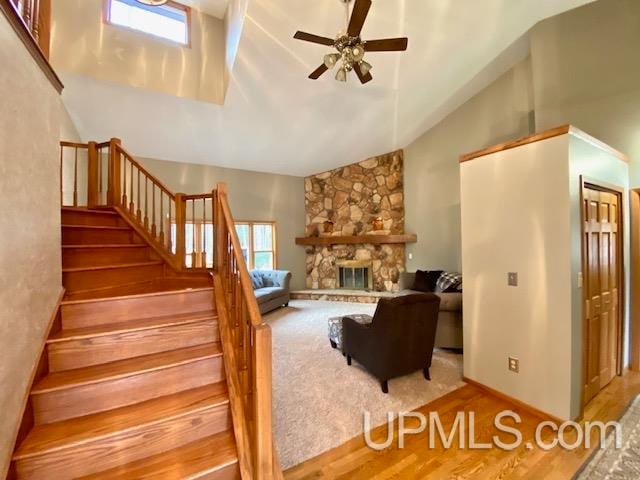 living room featuring ceiling fan, a fireplace, wood-type flooring, and lofted ceiling