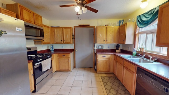 kitchen featuring appliances with stainless steel finishes, a textured ceiling, light tile patterned floors, sink, and ceiling fan