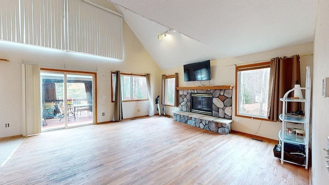 living room featuring high vaulted ceiling, light wood-type flooring, rail lighting, and a fireplace