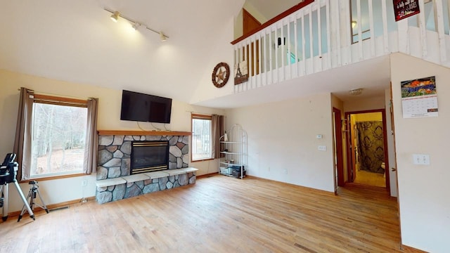 living room with hardwood / wood-style floors, a fireplace, a high ceiling, and track lighting