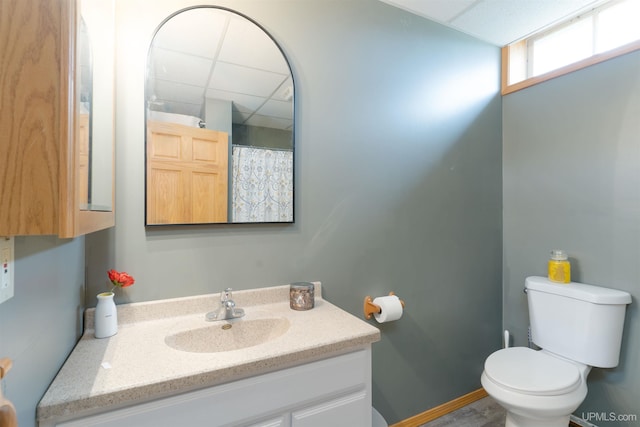 bathroom with a drop ceiling, vanity, toilet, and a shower with curtain