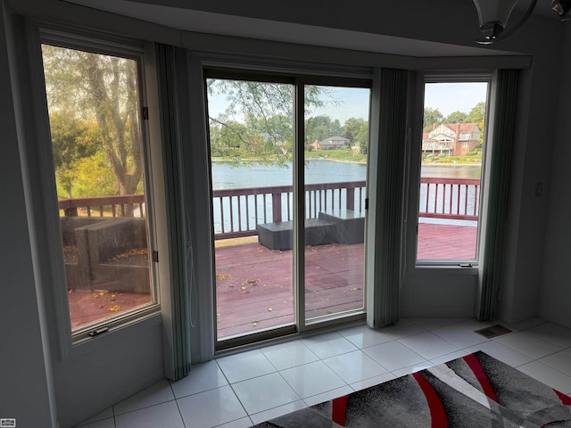 entryway with a wealth of natural light, light tile patterned floors, and a water view