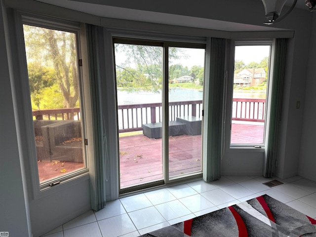 doorway to outside featuring a water view and light tile patterned floors