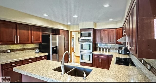 kitchen featuring light stone counters, decorative backsplash, sink, exhaust hood, and appliances with stainless steel finishes