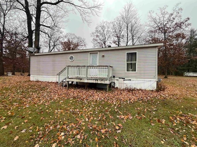 back of property with a wooden deck and a yard