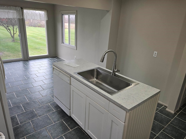 kitchen featuring white dishwasher, white cabinets, sink, and a kitchen island with sink