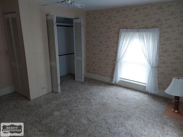 unfurnished bedroom featuring ceiling fan and carpet