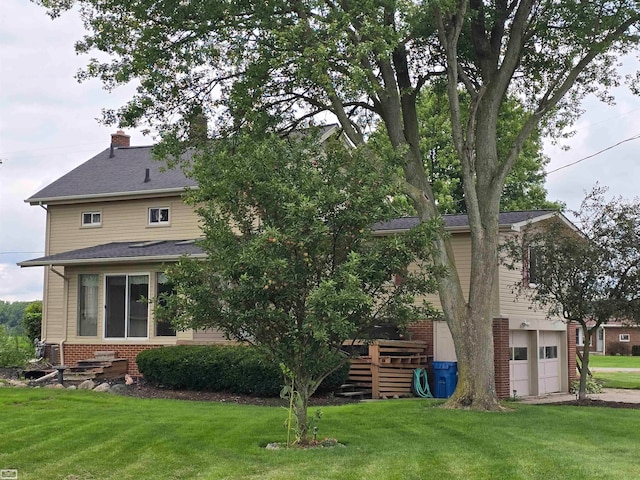 back of house featuring a garage and a lawn