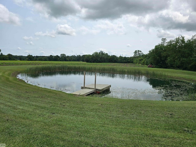 view of dock with a lawn and a water view