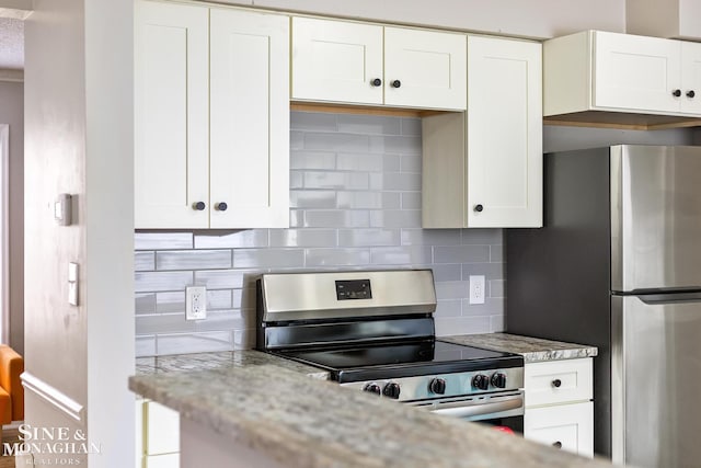 kitchen featuring white cabinets, light stone countertops, decorative backsplash, and appliances with stainless steel finishes