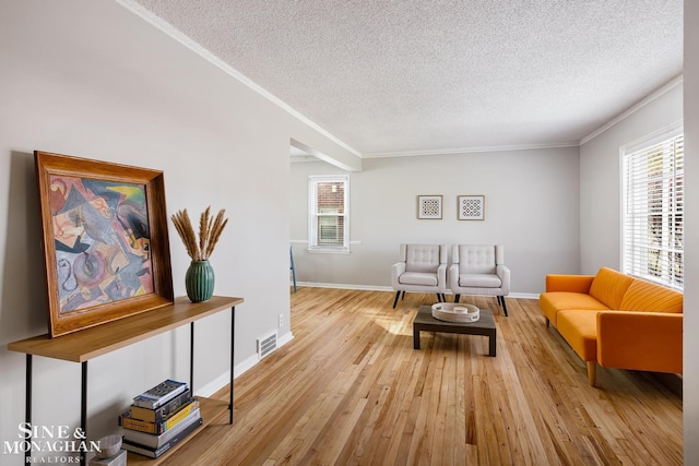 sitting room with a wealth of natural light, a textured ceiling, light hardwood / wood-style flooring, and crown molding