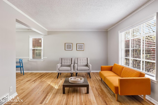 living room featuring plenty of natural light, light wood-type flooring, crown molding, and a textured ceiling