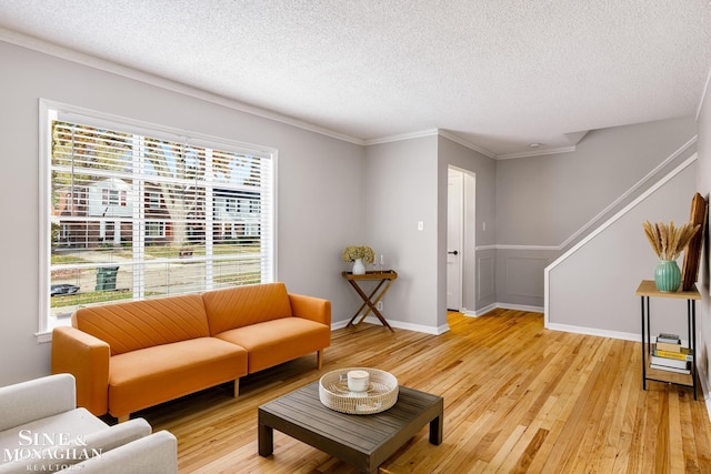 living room featuring a wealth of natural light, ornamental molding, a textured ceiling, and hardwood / wood-style flooring