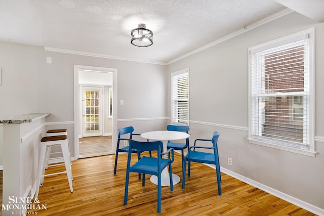 dining room featuring ornamental molding, a healthy amount of sunlight, and light hardwood / wood-style flooring