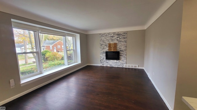 unfurnished living room featuring a stone fireplace and dark hardwood / wood-style flooring