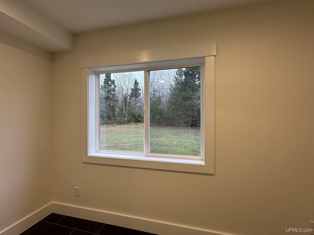 11881 N Junet Rd, Ironwood, MI 49938 - empty room with healthy amount of natural light, dark tile patterned floors, and baseboards