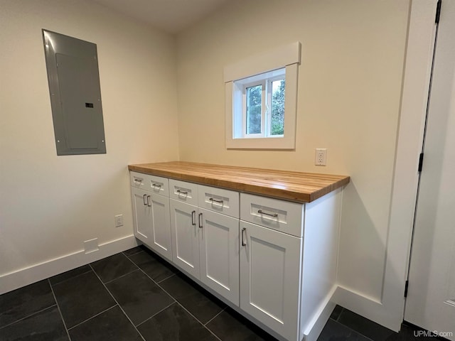 clothes washing area with dark tile patterned flooring and electric panel