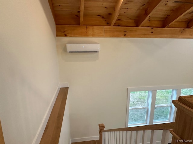 interior space featuring a wall unit AC, beamed ceiling, and wood ceiling