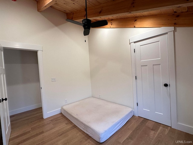 unfurnished bedroom featuring beamed ceiling, wood-type flooring, and wooden ceiling