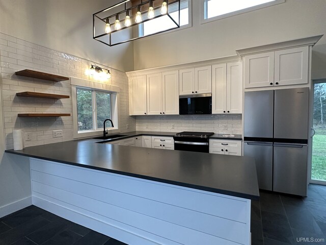 11881 N Junet Rd, Ironwood, MI 49938 - kitchen featuring appliances with stainless steel finishes, open shelves, a peninsula, dark countertops, and tasteful backsplash