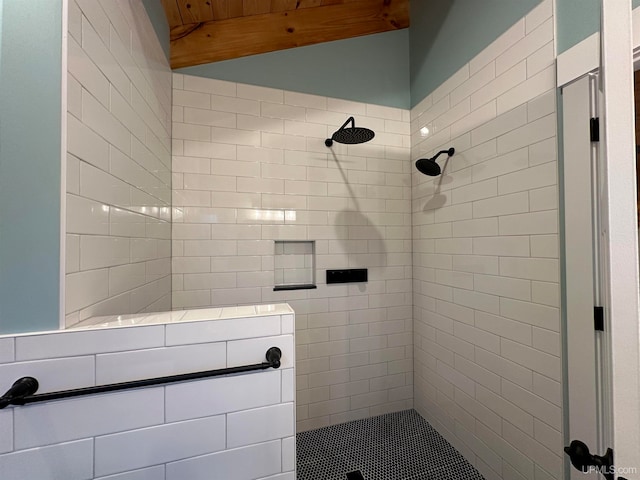 bathroom with a tile shower and beam ceiling