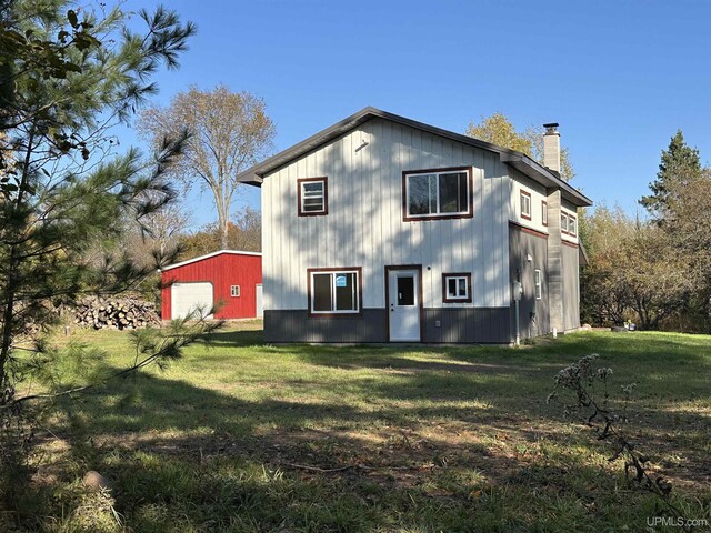 11881 N Junet Rd, Ironwood, MI 49938 - rear view of property with a chimney, a garage, an outdoor structure, and a lawn