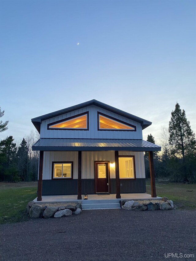 11881 N Junet Rd, Ironwood, MI 49938 - back of house at dusk featuring covered porch, metal roof, board and batten siding, and a standing seam roof