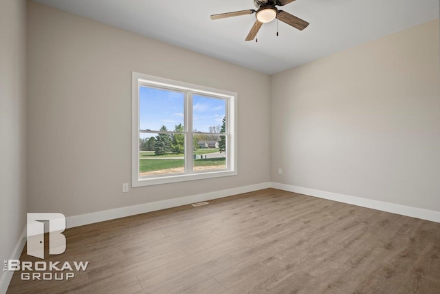 spare room featuring baseboards, visible vents, wood finished floors, and a ceiling fan