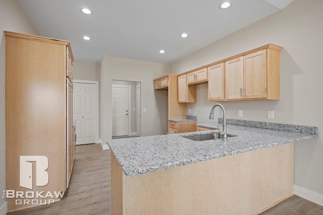 kitchen featuring a sink, light brown cabinetry, light stone countertops, recessed lighting, and a peninsula
