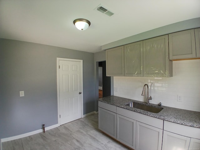 kitchen with tasteful backsplash, light wood-type flooring, and sink