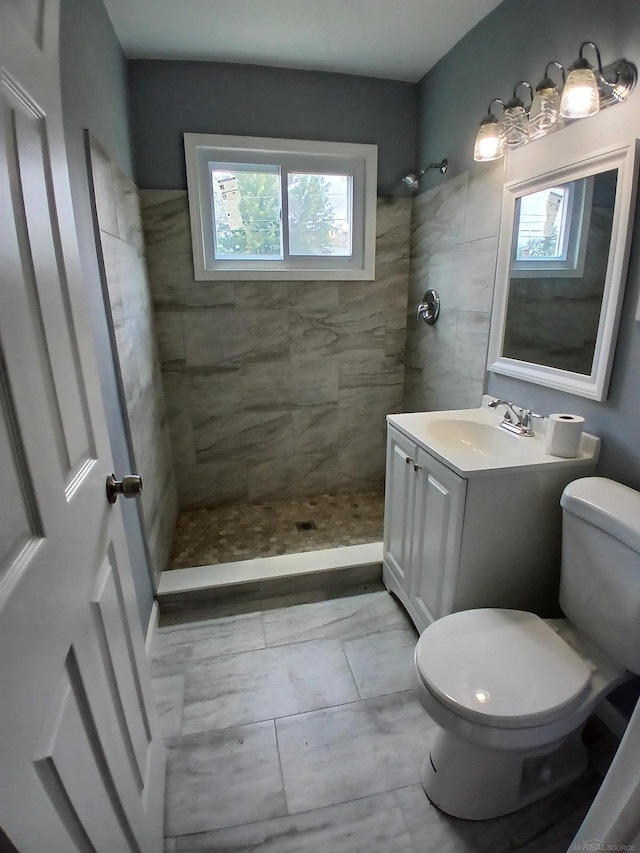 bathroom with toilet, vanity, and tiled shower