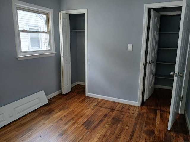 unfurnished bedroom featuring dark hardwood / wood-style floors, a walk in closet, and a closet