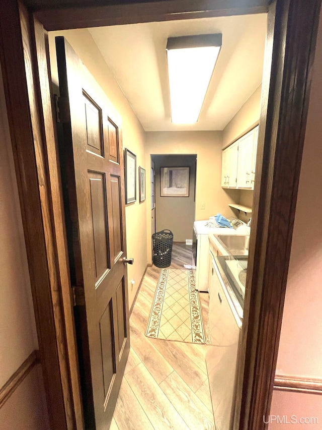 laundry room featuring cabinets, independent washer and dryer, and light hardwood / wood-style floors