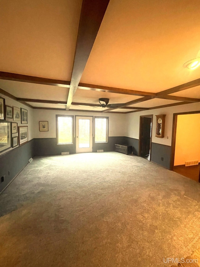 unfurnished living room with beamed ceiling and carpet flooring