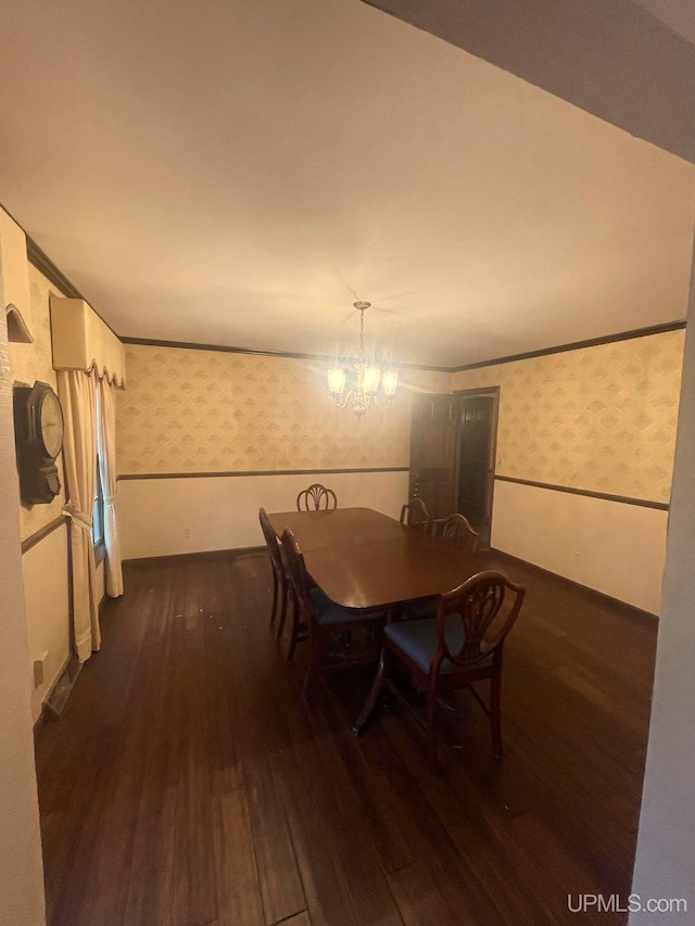 dining room featuring dark hardwood / wood-style flooring, ornamental molding, and an inviting chandelier